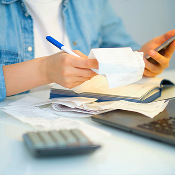 person looking at receipts and phone at desk person looking at receipts and phone at desk