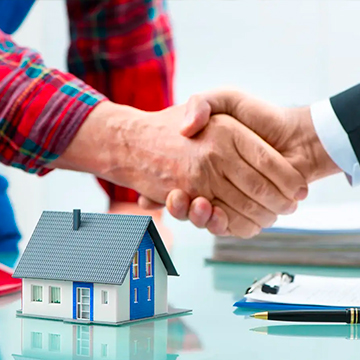 Two people handshaking while a miniature house and documents lie on a table Two people handshaking while a miniature house and documents lie on a table