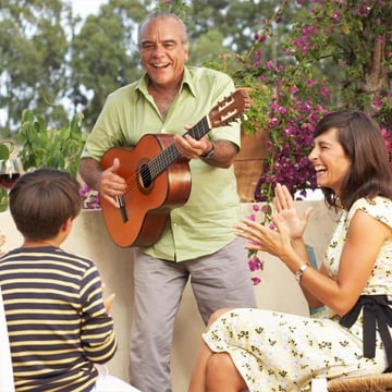 middle aged man playing guitar and singing songs to his younglings