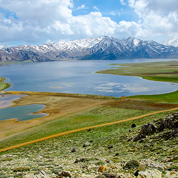 large lake on green plains with snowy mountains on the background  large lake on green plains with snowy mountains on the background