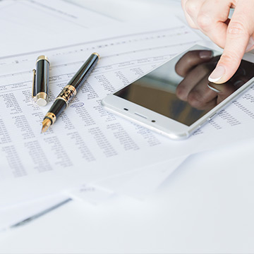 Finger touching screen of smartphone at desk Finger touching screen of smartphone at desk