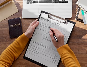 flat lay visa application form, passport, and laptop