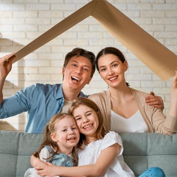 family smiling while holding cardboard shaped like a roof