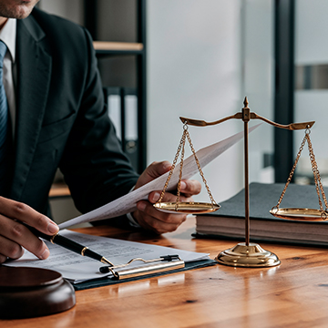 Lawyer reviewing buy-to-let rental regulations and compliance documents in Spain with justice scale on desk Lawyer reviewing buy-to-let rental regulations and compliance documents in Spain with justice scale on desk