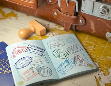 Раскрытый паспорт, лежащий на столе с картой и чемоданом