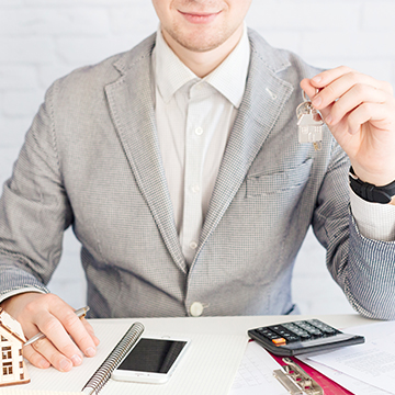 Real estate agent holding house keys with rental agreement, calculator, and contract on desk — representing landlord rights and rental contract essentials in Turkey Real estate agent holding house keys with rental agreement, calculator, and contract on desk — representing landlord rights and rental contract essentials in Turkey