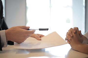 A person handing a pen to another person for signature A person handing a pen to another person for signature